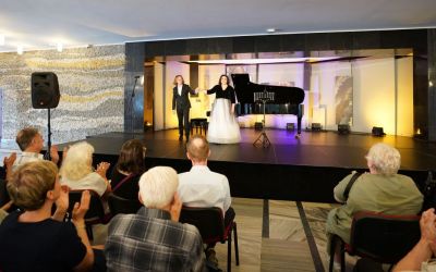 zdjęcie z perspektywy widowni, na scenie przed fortepianem stoją Joanna Rot i Michał Rot, widownia klaszcze